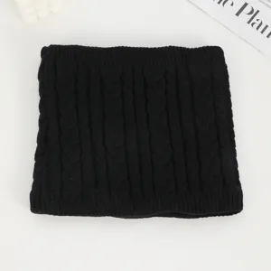 Detailansicht eines schwarzen Strickhalswärmers mit weicher Zopfmusterstruktur im Winter.