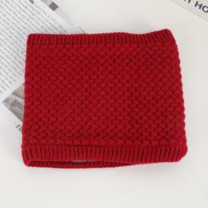 Close-up view of a cozy red knitted neck warmer with textured stitch pattern detail.