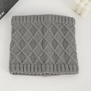 Grauer Strick-Halswärmer Detail mit weicher Zopfmuster-Textur und warmem Material.