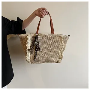 Modieuze geweven stroten tas met bruine handvatten en franjes voor een zomerse strandvakantie.