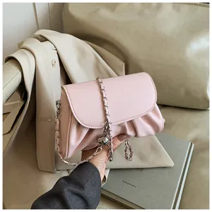 Detailgezicht van roze zachte lederen crossbodytas met chique ketting en elegante textuur.
