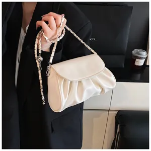 Gedetailleerd overzicht van een zachte lederen crossbodytas met ketting en geplooid ontwerp.