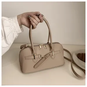 Close-up detail of stylish beige retro top-handle shoulder bag with metal buckle accent.