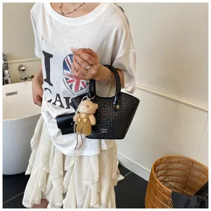Woven bucket bag detail showing stylish black leather tote design with cute bear charm.