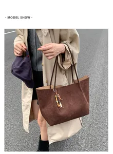 Detail view of brown suede shoulder tote bag with wood bead charm in street scene.