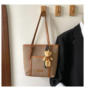 Detailed view of the stylish woven shoulder tote bag with cute bear pendant and practical pocket.