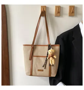 Casual straw tote shoulder bag with brown leather trim and cute bear pendant detail.