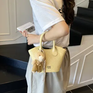 Yellow woven handbag for women, stylish bucket bag with cute bear pendant for daily commute.