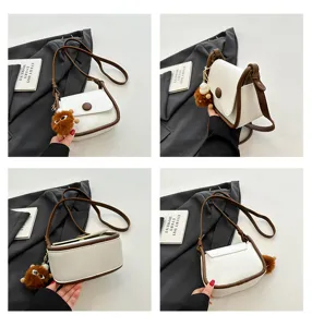 Detail view of the stylish white and brown crossbody bag showing textured PU leather and cute plush charm.