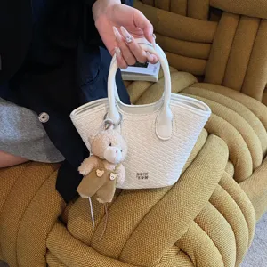Summer woven bucket handbag for women, trendy commuter basket bag with cute bear charm.