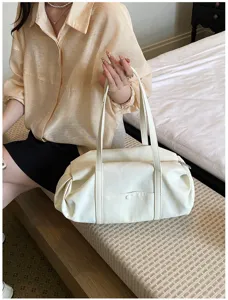 Detailed view of a stylish white shoulder bag with dual handles and soft fabric, perfect daily use.