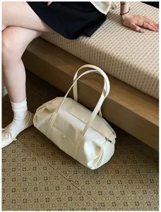 Detailed shot of cream white ruched shoulder bag, soft faux leather duffel style lifestyle view.