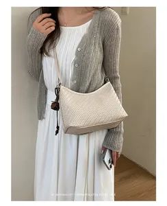 Primo piano dettagliato della elegante borsa a spalla intrecciata, con texture raffinata.