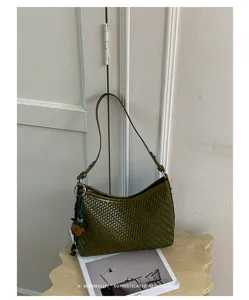 Primo piano dettagliato di una elegante borsa a spalla intrecciata verde scuro in stile.