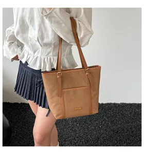 Detailed view of casual brown woven tote bag with PU leather straps and front pocket.