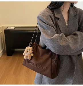 Brown vintage suede tote bag with cute fluffy bear charm detail and shoulder strap.