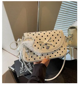 Detailed view of a sweet Korean style polka dot shoulder bag with bow and pearl lace pendant.