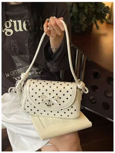 Close-up of sweet polka dot shoulder bag with cute bow and metal heart charm detail.