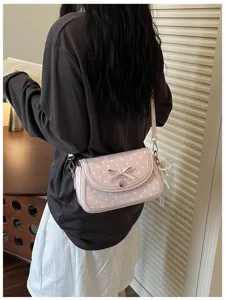 Pink polka dot shoulder bag detail featuring a sweet bow and delicate heart pendant accessory.