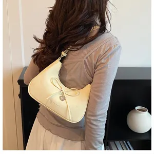 Détail du sac croissant minimaliste, design élégant avec nœud et charmant pendentif cœur.