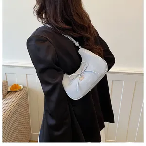 Vue détaillée du sac porté épaule croissant gris clair élégant avec nœud et charm cœur.