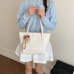 Stylish white large capacity tote bag for women, versatile shoulder commuter bag with cute bear charm.