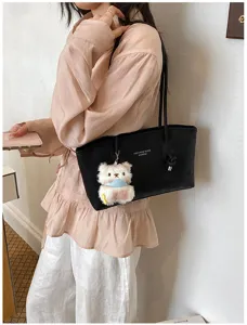 Detail view of a black PU leather shoulder tote bag with cute plush bear pendant for women.