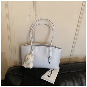 Detailed view of stylish light blue women shoulder tote bag with cute bear keychain charm.