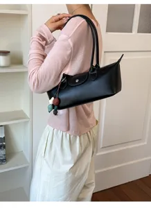 Detailed view of a chic black leather underarm shoulder bag with a classic flap and charm.