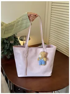 Detailed view of stylish pink tote bag with cute bear pendant, premium leather texture.