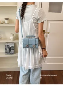 Detail shot of the blue denim crossbody square bag with metal turn-lock and top handle.