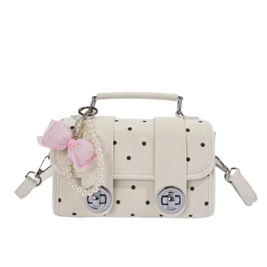 Cream white polka dot crossbody bag with pearl bow and metal locks for women daily use.