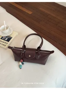 Detailed view of the chic dark brown leather handbag featuring top handles and snap flap.