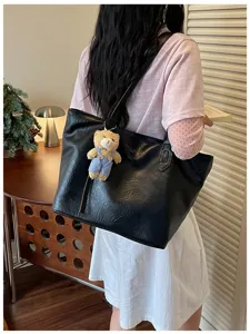 Minimalist black leather tote bag detail with cute bear pendant for daily commuting and travel