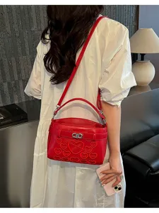 Red leather crossbody handbag with heart embroidery, stylish shoulder bag for women.
