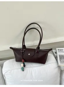Stylish brown leather underarm shoulder bag for women, trendy east-west design with chic beaded charm.