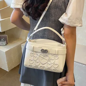 White heart embroidered top handle crossbody bag with stylish belt design and chain strap.
