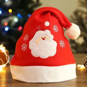 Gros plan détaillé du bonnet de Noël rouge avec pompon blanc et broderie détaillée du Père Noël.