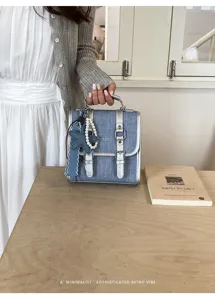 Vue détaillée du sac à dos rétro en denim élégant avec brides argentées et charm perlé.