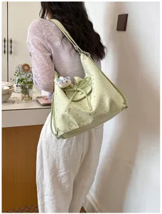 Vue détaillée d'un sac cabas vert clair à motif d'étoiles avec un nœud et une bandoulière.