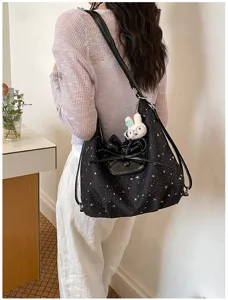 Vue détaillée du sac cabas noir imprimé d'étoiles avec un nœud et un pendentif lapin.