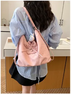 Détail de sac cabas rose à imprimé étoiles avec nœud mignon et bandoulière pratique.