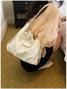 Vue détaillée du sac cabas blanc à imprimé étoiles avec nœud et pendentif lapin en peluche.