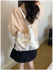 Vue rapprochée d'un sac porté épaule blanc à motif d'étoiles, élégant nœud et jolie peluche.