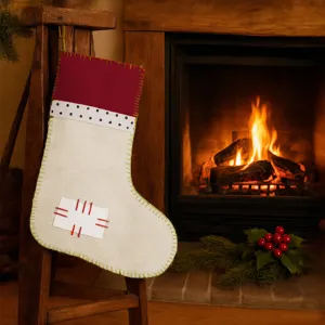 Close-up of linen Christmas stocking hanging on wooden stand near cozy fireplace scene.