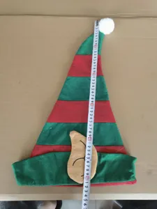 Close-up view of red and green striped Christmas elf hat with large ears and white pom-pom.