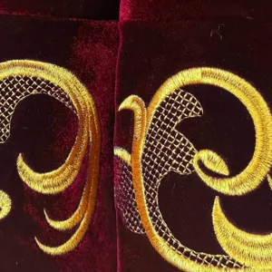 Luxury burgundy velvet Christmas tree skirt detail featuring intricate gold embroidery.