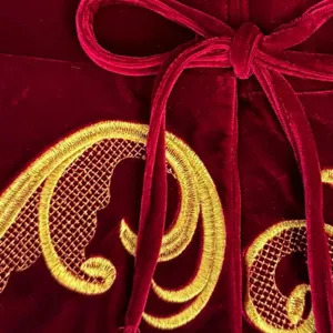 Red velvet Christmas tree skirt detail showing elegant gold embroidery and a soft velvet bow tie.