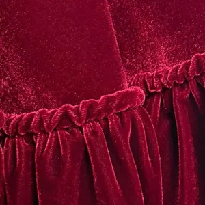 Close-up detail of luxurious burgundy velvet fabric with elegant ruffled edges and soft texture.