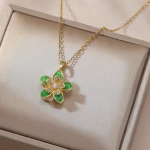 Close-up of gold flower pendant necklace with green enamel and sparkling zirconia stones.